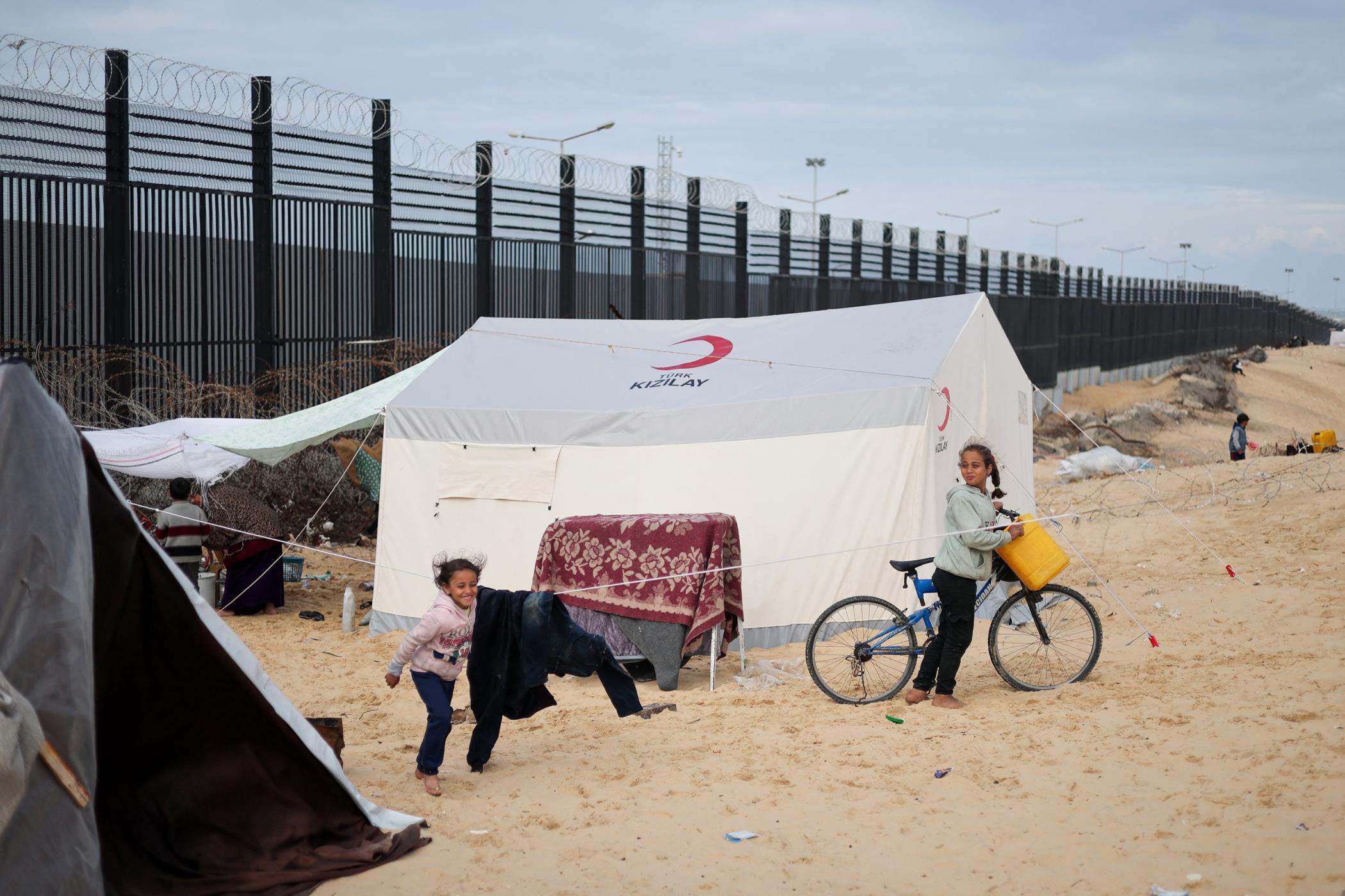 Children stand next to a tent as displaced Palestinians, who fled their houses due to Israeli strikes, shelter at a tent camp, at the border with Egypt, in Rafah in the southern Gaza Strip,  Jan. 26, 2024. (Reuters Photo)