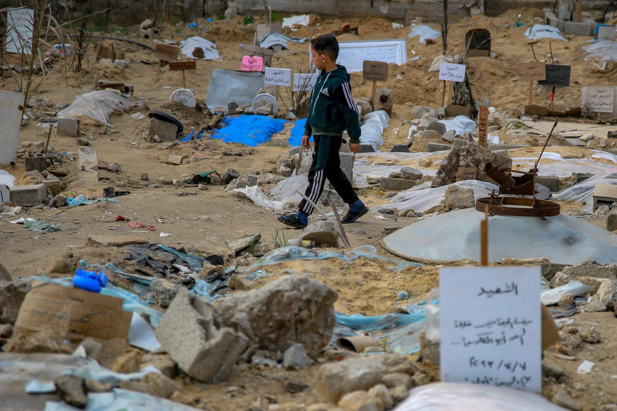 A Palestinian boy walks inside a makeshift cemetery wher<em></em>e people killed in Israeli bombing are buried in shallow tombs, Gaza City, Gaza, Palestine, Jan. 9, 2024. (AFP Photo)